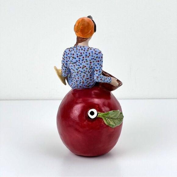 CARRIANNE L HENDRICKSON woman with beak hat sitting on apple sculpture 2… - Picture 5 of 16